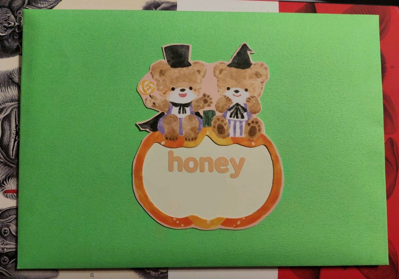 a photo of the front of a bright green envelope. there is cutout in the center of the envelope of two cute bears sitting on top of a pumpkin. the pumpkin center has been cut out and has the name Honey on the front in cute bubble letters