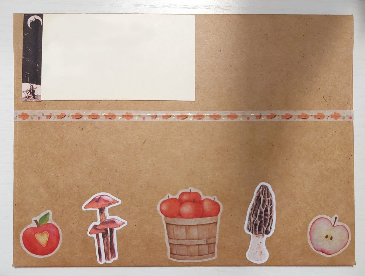 a photo of the back of a brown envelope. there are mushroom and apple stickers along the bottom