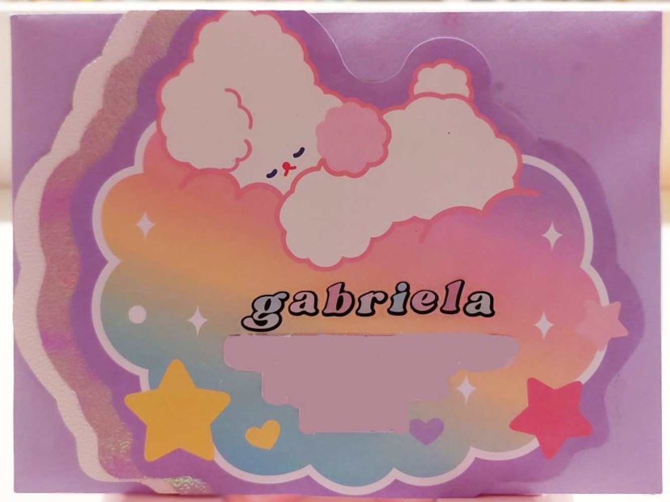 photo of the front of an envelope. the envelope front has a cartoony, cute bunny sleeping on a pastel cloud with the name 'gabriela' pasted on